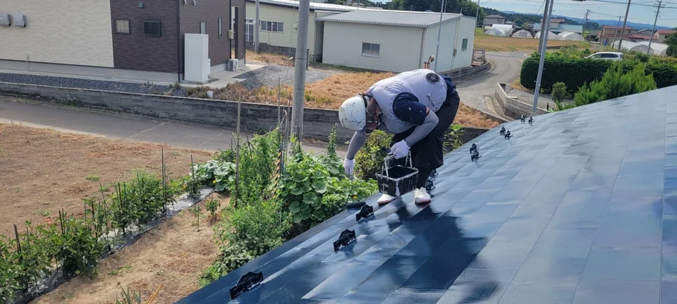 屋根の塗装作業を進める職人